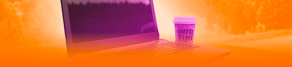 Laptop en koffiebeker op bureau.